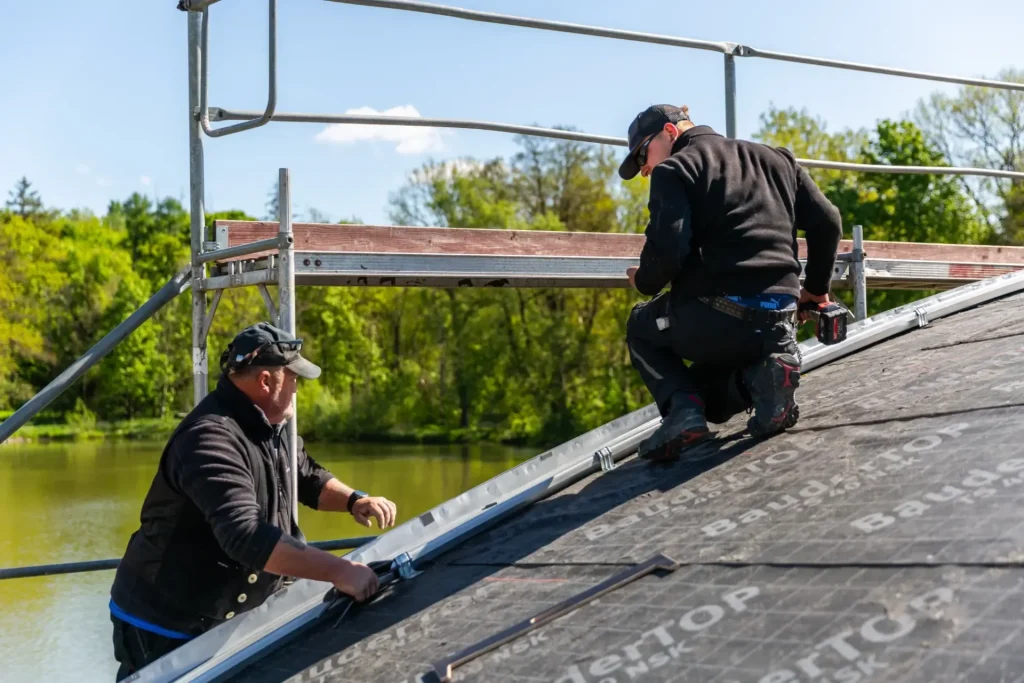 Zwei Mitarbeiter von Spörl und Nietner bei der Eindeckung mit Metallpaneele auf dem Dach der Seebühne in Lichtenberg